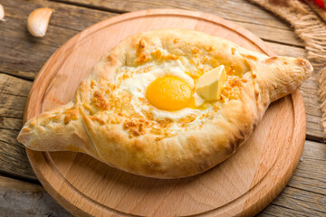 ajara Khachapuri with cheese, egg and butter, georgian kitchen on wooden table