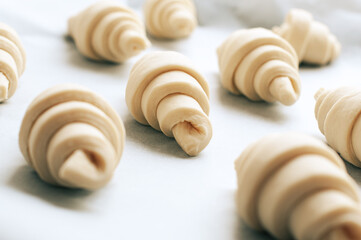 Fototapeta na wymiar Semifinished croissant on a baking sheet. Puff pastry baking.