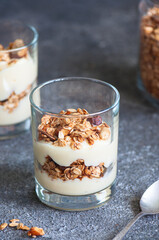 Granola with yogurt dessert in a glass. Gray background. Healthy eating or breakfast concept.