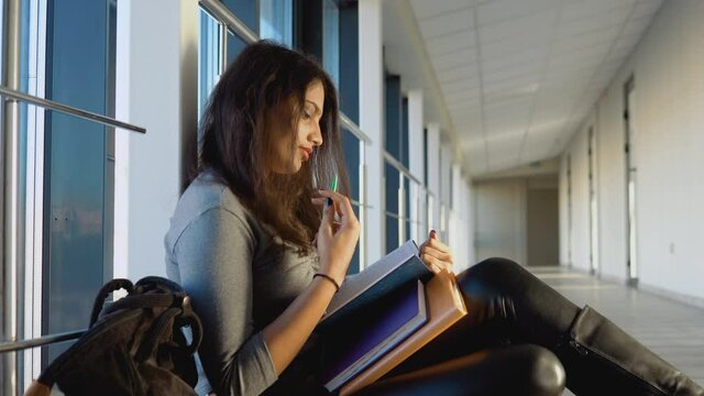Indian girl student sitting on the floor with a books in the university. New modern fully functional education facility. Education abroad