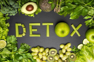  Top view of fresh green vegetables and fruits with word detox on a black background. Detox diet,...