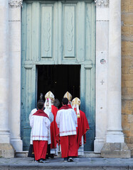 Row of male religious church ministers going into church, back view