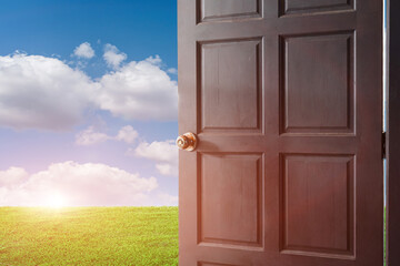open door with a view of green meadow field at sunrise sky background.