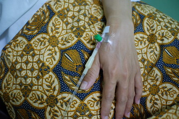 A woman's hand is attached to an IV needle to support health. 