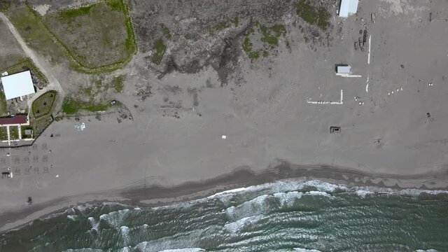 Long sandy beach with buildings AND tourist attractions along endless blue sea with white foaming waves against hills aerial view. Montenegro, Ulcinj, Velika Plaza