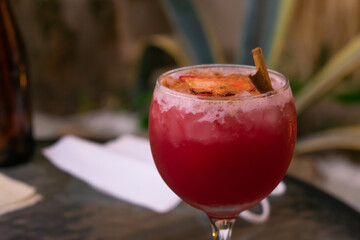 Close up of a cold red aromatic seasonal cocktail made with berries, cinnamon, and spices served in a beautiful round frosted glass cup. Blurred rustic background.  Pubs, bars and nightlife .