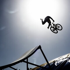 dirtbike bmx rider jumps against sun