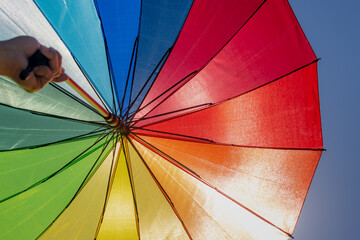 Selective focus of colourful rainbow umbrella with uprisen angle and blue sky as background, The...