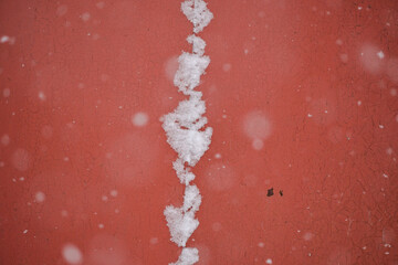 Background of red color. The metal forged leaf with design against the background of the falling...