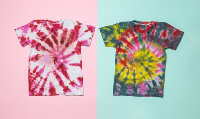 Neatly stacked two tie dye T-shirts on a pink and blue background. Flat lay.