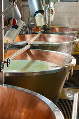 Process of making wheels of parmigiano-reggiano parmesan cheese on small cheese farm in Parma, Italy