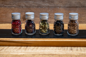 Professional set of gin spices in small bottles, pink pepper, hibiscus flowers, juniper berries, cardamom and coriander seeds