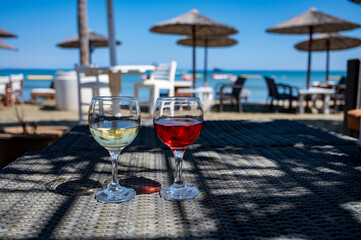 Drinking of cold rose and white wines in lounge bar on sunny sandy beach with blue sea water on background