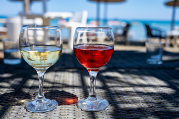 Drinking of cold rose and white wines in lounge bar on sunny sandy beach with blue sea water on background