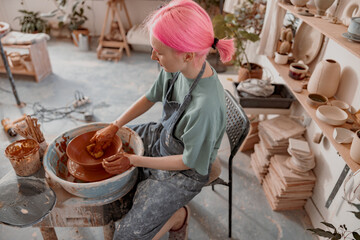 Female crafter making clay dishes in pottery room