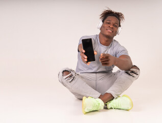 Young afro black man showing the screen of his smartphone looking confident and optimistic wearing...
