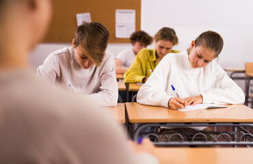 Teenage boy and girl studying in classroom during lesson.