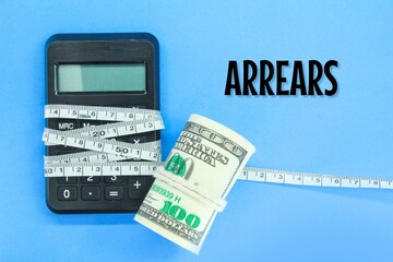 banknotes and calculators wrapped with measuring tape with the word arrears. the concept of arrears