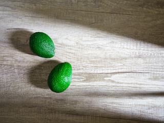 two avocados on wooden surface