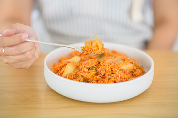 A woman is scooping her homemade kimchi fried rice.