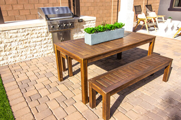 Wooden Table And Benches On Pavers In BBQ Area Patio