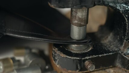 A close-up of tailor installs rivets on the collar of black leather jacket using special vintage machine. Hands of an elderly master are set with large nails that install handmade rivets. slow motion - Powered by Adobe