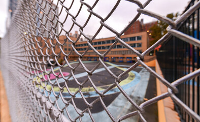 Fototapeta na wymiar Closed playground for kids and pupils during COVID19 pandemic. View of a fence with blurry background. Empty space without children.