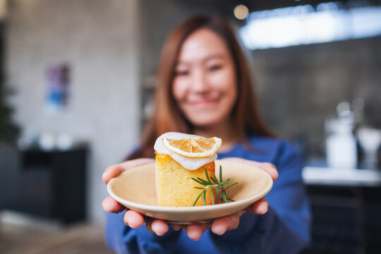 Blurred image of a young asian woman holding and showing a piece of lemon pound cake