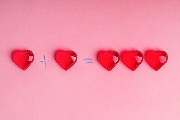 Flat lay with love math formula of two red heart shaped decoration making three hearts on pink background. Making family concept. Image with copy space