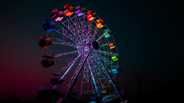 A colourful Ferris wheel spinning slowly during a dark night in an endless loop