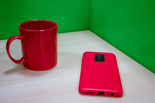 mug rojo en oficina con celular y aud&iacute;fonos
