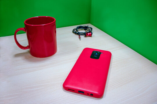 mug rojo en oficina con celular y aud&iacute;fonos
