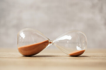 Hourglass on table, Sand flowing through the bulb of Sandglass measuring the passing time. countdown, deadline, Life time and Retirement concept