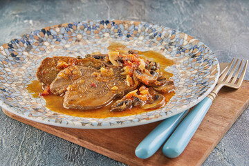 Veal tongue with tomato sauce, mushrooms and capers. French gourmet cuisine - obrazy, fototapety, plakaty