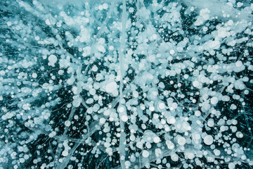 Texture of beautiful blue ice with cracks and air bubbles in the frozen lake. Winter nature background.