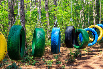 Old painted car tires suspended between trees in a rope park