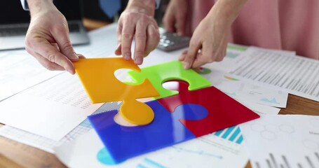 Business people putting together colorful puzzle at table in office closeup 4k movie slow motion