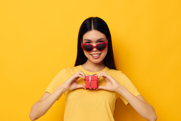 pretty brunette wearing sunglasses small gift box yellow background unaltered