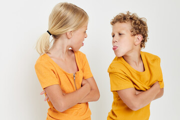 Cute stylish kids in yellow t-shirts standing side by side childhood emotions light background unaltered