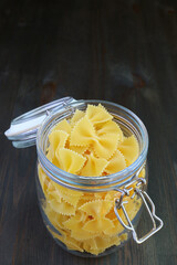 Uncooked Farfalle Pasta in a Glass Jar Isolated on Black Wooden Table