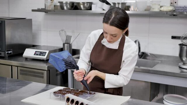 Chocolatier pours the chocolate into the molds. Pastry bag chef fills the hot melted chocolate into a silicone mold.