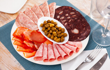 Delicious meat platter - sliced dry-cured pork loin, salami and blood sausage on serving plate with...