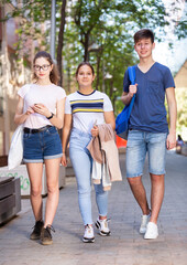 Portrait of happy teenagers strolling through modern city streets on sunny summer day