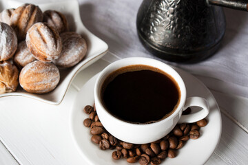 a cup of black coffee and sweets for breakfast on a white wooden table