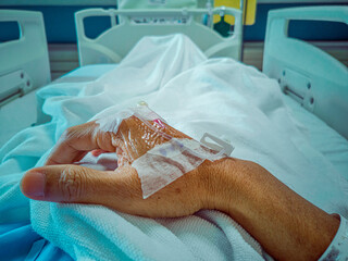 Coronavirus COVID-19 patient's arm, saline needle, and medicine on patient's arm Fighting during normal hospital treatment. Soft focus. Shallow focus effect.