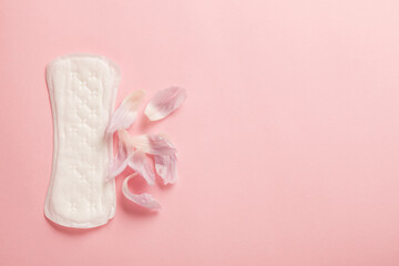 Menstruation pad with flower petals on pink background, woman critical days health care, female gynecological concept, menstruation cycle