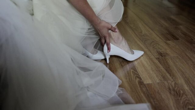 bride puts on wedding shoes in the morning room
