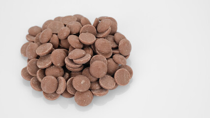Milk chocolate callets on white background. Chocolate chips. Confectionery concept