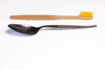 Wooden toothbrush and spoon horizontally on white background. Copy space available