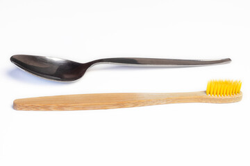 Spoon and eco wooden tote brush horizontally on white background. Concept of dental hygiene